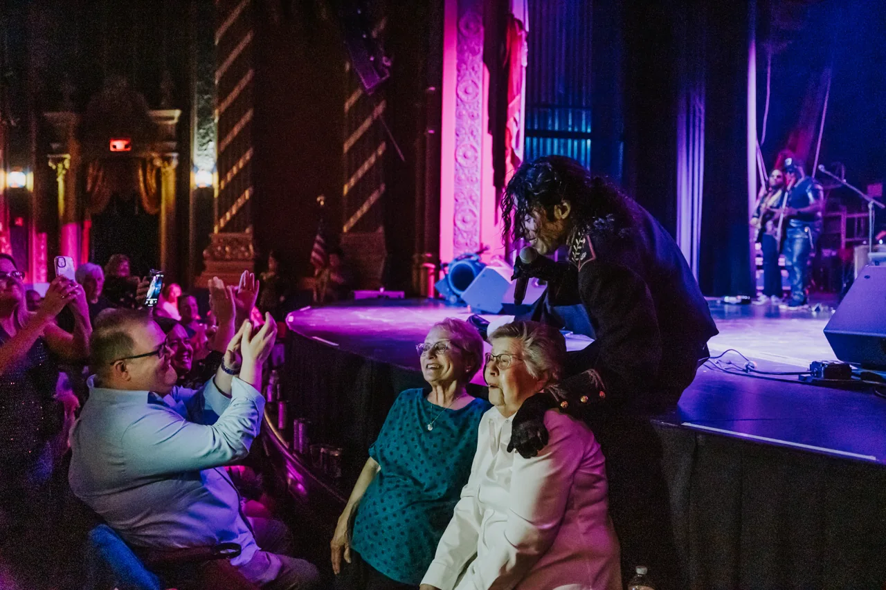 Who’s Bad performer leans down to greet smiling concertgoers at the edge of the stage
