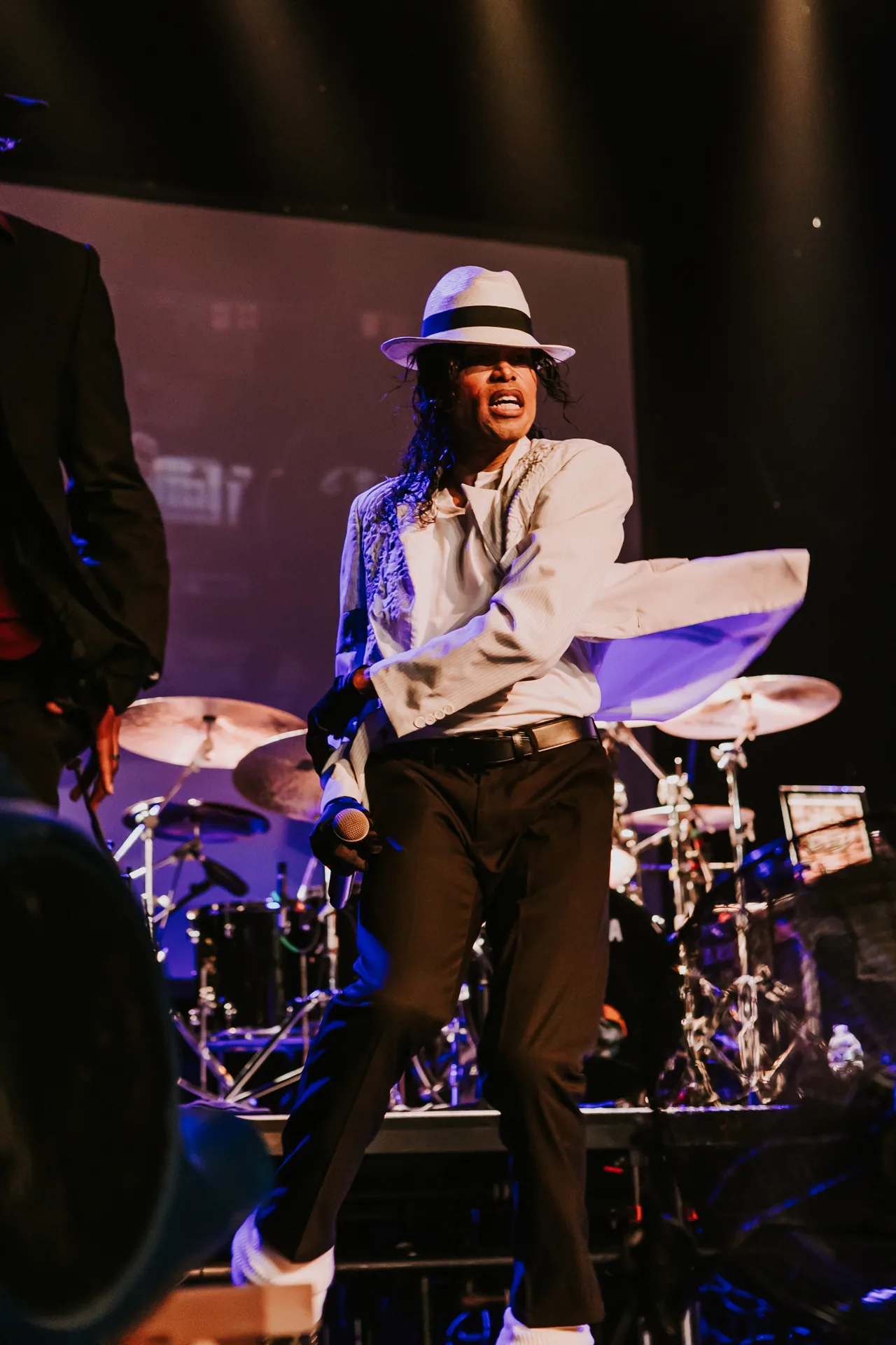 Who’s Bad vocalist sings in a white shirt and fedora with the drummer behind him