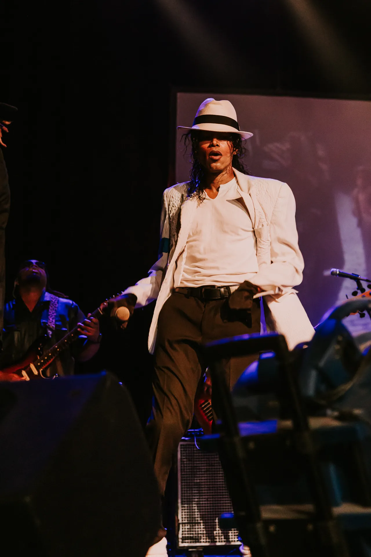 Who’s Bad performer in a white shirt and fedora poses with one knee lifted